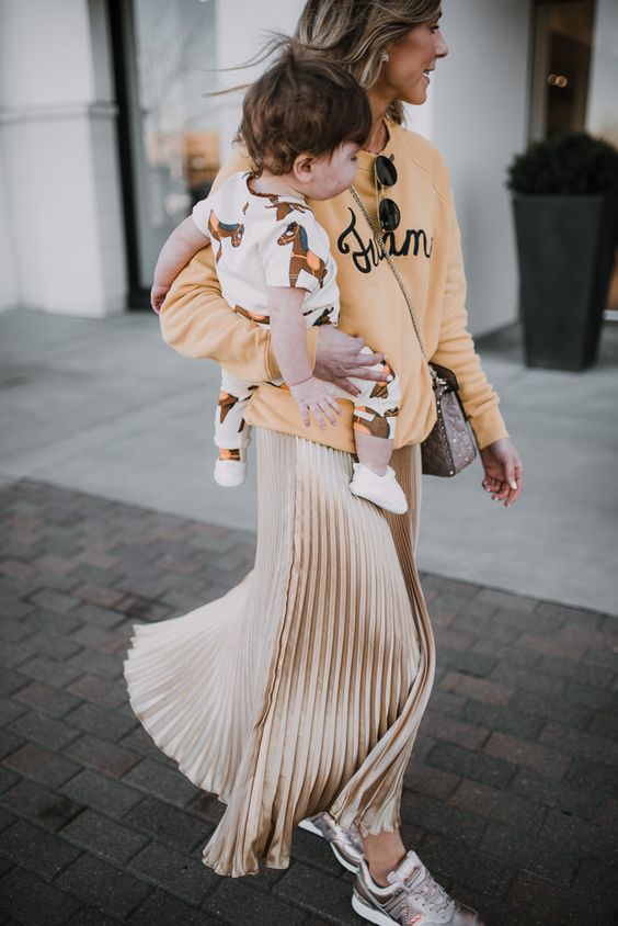 an Easter look with a yellow printed sweatshirt, a tan metallic pleated maxi skirt, grey trainers and a grey bag