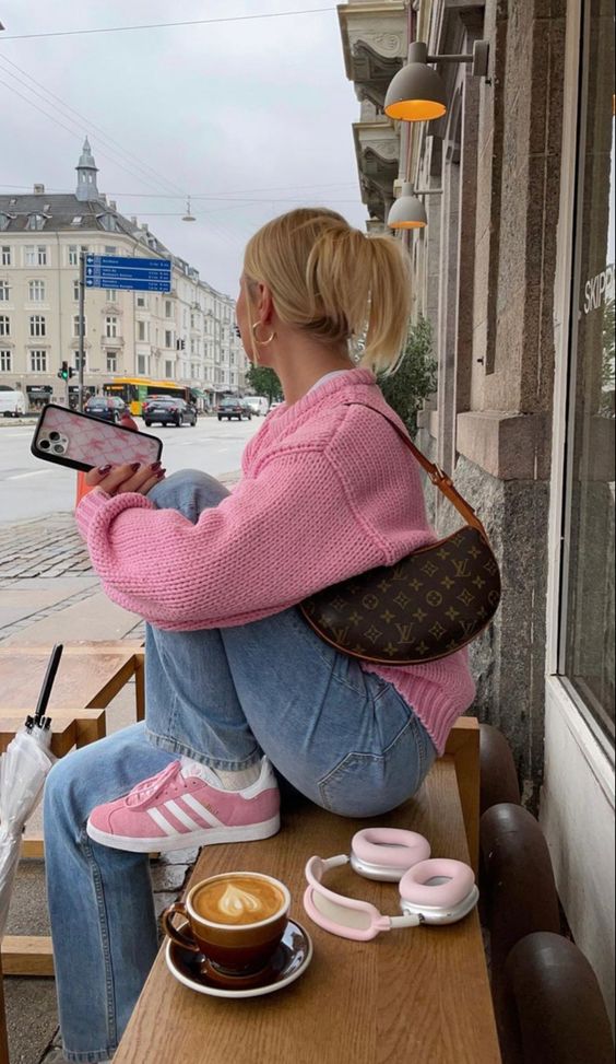 an Easter outfit with a pink jumper, blue jeans, pink sneakers and a printed baguette bag is lovely and comfy