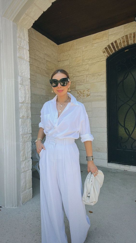 An all white look with a button down, palazzo pants, statement accessories and a neutral bag