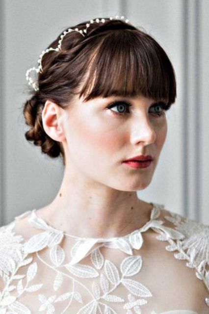 an elegant braided low updo with a pearl headband and classic fringe are a chic and classy combo for a bride