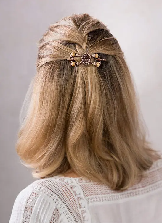 an elegant half updo with a braided top and straight hair down plus curled ends and a chic hair piece
