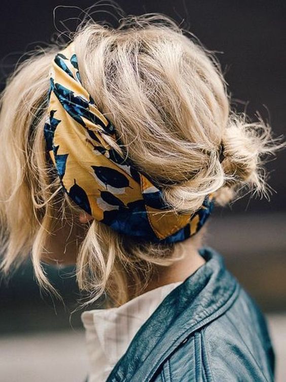 a super messy low updo with bangs framing the face and a bold printed headband to accent the look as much as possible