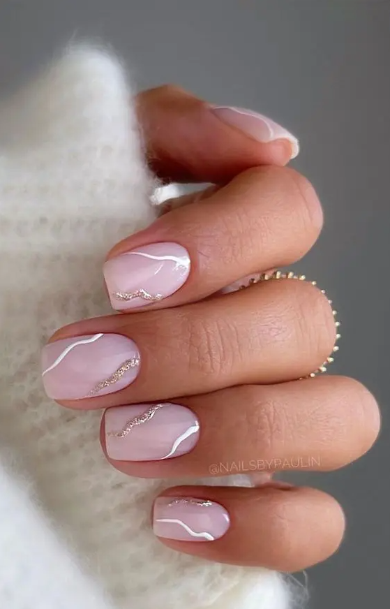 beautiful short square nails in blush pink, with abstract wavy white and gold glitter patterns are amazing for a glam look