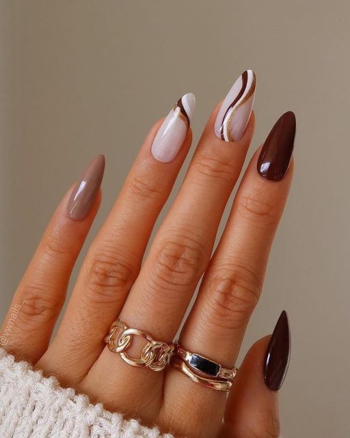 long almond nails in deep brown and greige, plus two swirl nails in milky white and with brown and copper touches