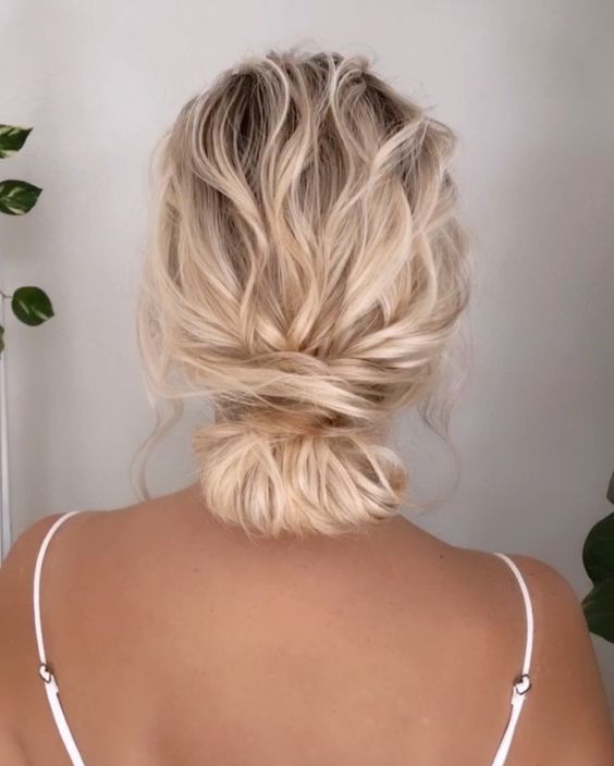 wavy hair styled in a low bun with a wavy top is a cool casual wedding hairstyle to rock