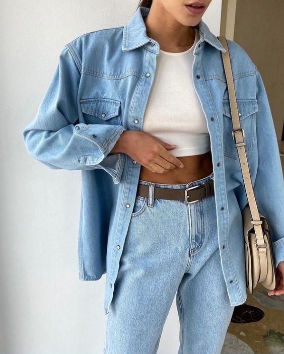 a 90s look with a white top, bleached jeans, a blue denim shirt and a tan bag is amazing