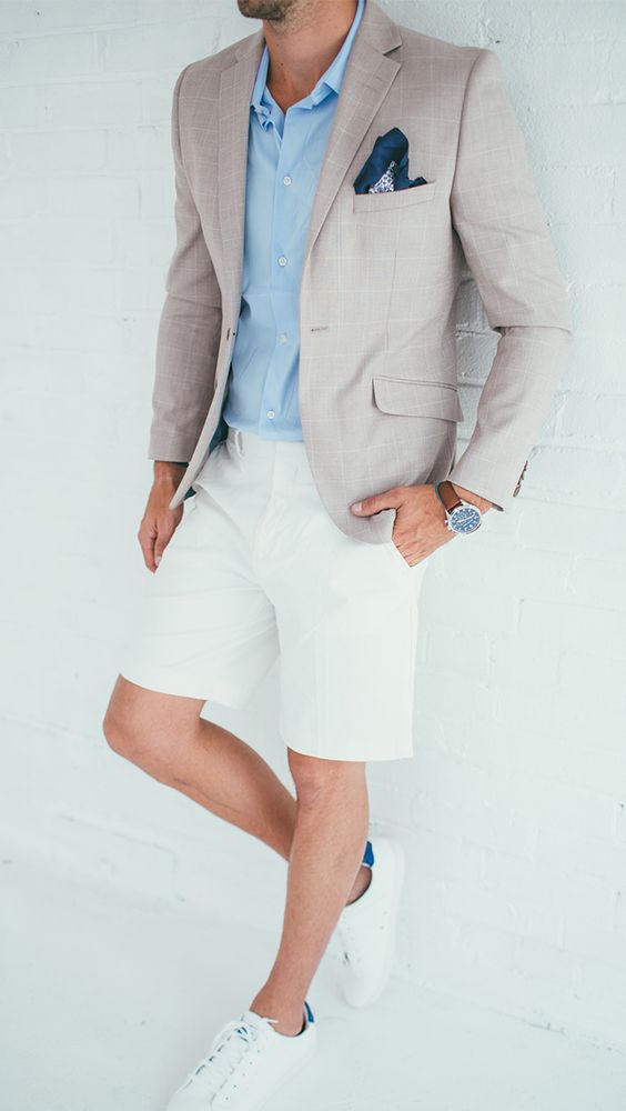 a beach wedding guest outfit with a blue button down, white shorts, a grey blazer, white sneakers