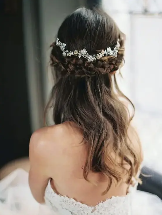 a beautiful half up hairstyle with a thick braided halo and a chic rhinestone floral hair vine is a lovely idea