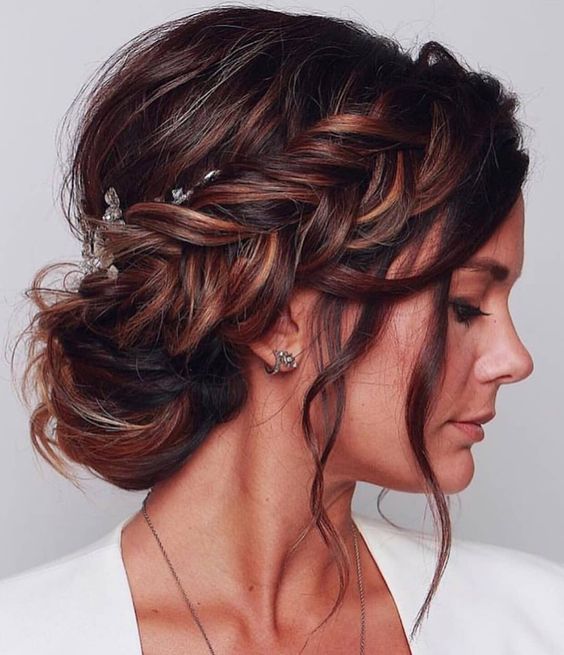 a beautiful messy wedding updo with a bump on top and a fishtail halo plus some face-framing hair