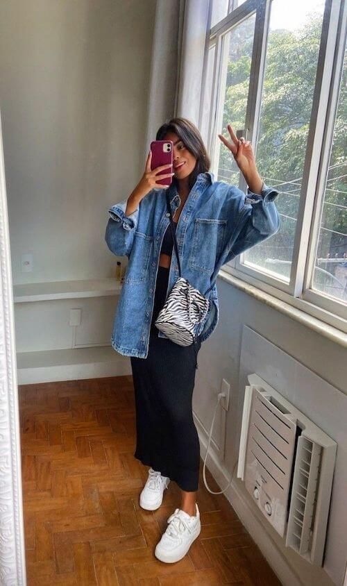 a black crop top, a maxi skirt, an oversized blue denim jacket, white trainers and a printed bucket bag