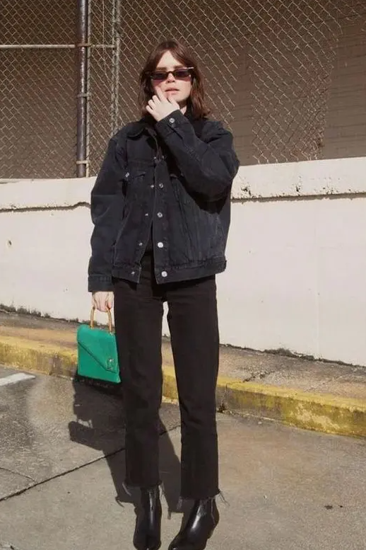 a black denim jacket, black jeans, black boots and a bold green bag to refresh the space