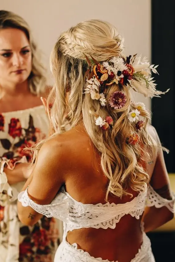 a boho wedding half updo with a double fishtail braid halo, waves down and a lot of dried blooms tucked in the hair