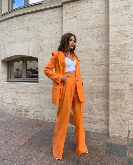 a bold orange pantsuit with an oversized blazer, a white crop top, palazzo pants, white shoes are a great look for graduation