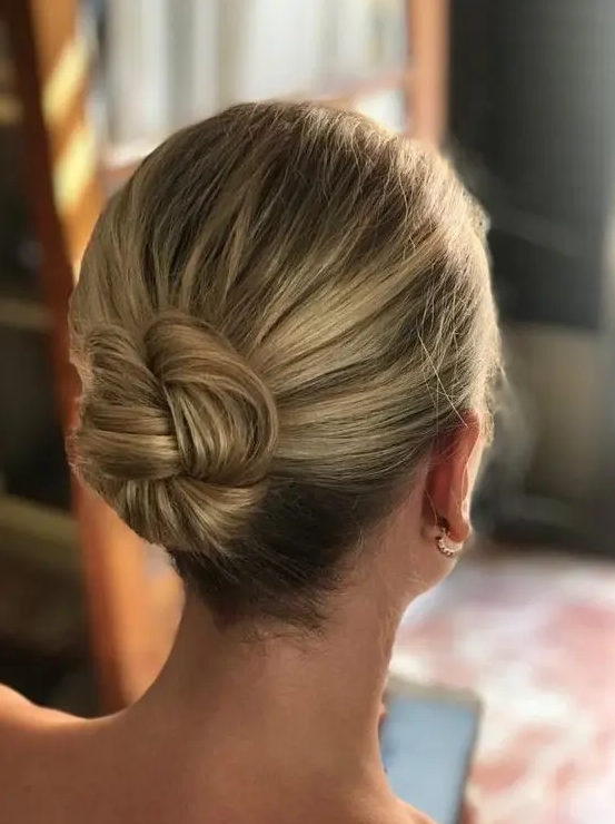 a braided bun with a volumetric top is a cool solution for a wedding if you have medium length or even short hair