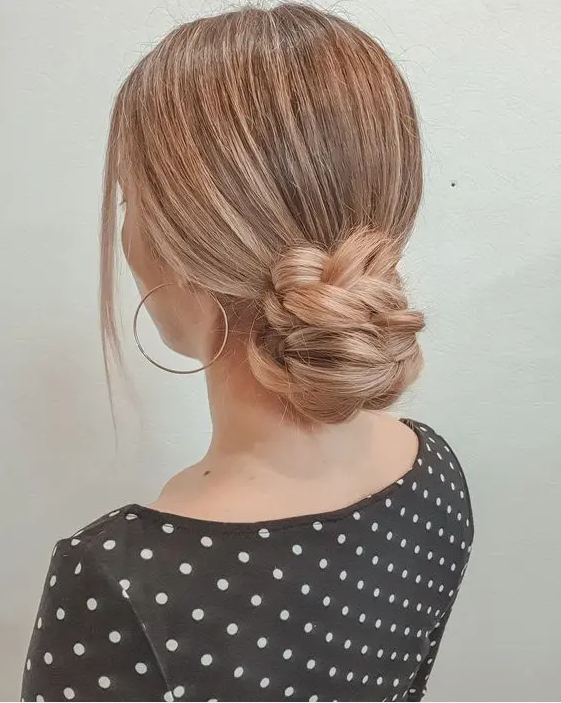A braided low bun with a sleek top and face framing hair is a catchy and cool solution for a any kind of party