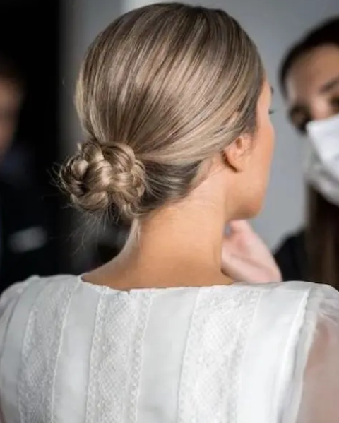 a braided low bun with a sleek top will be a great solution for a bridal  look with a slight boho feel