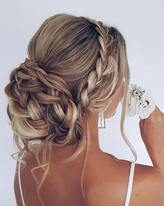 a braided wedding updo with a braided halo, a bump on top and a braided bun plus some locks down is chic and cool