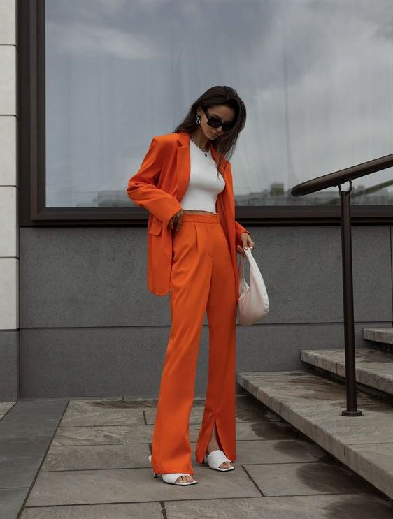 a bright outfit with an orange pantsuit, a white crop top, white shoes and a small bag is a super cool and catchy look for graduation