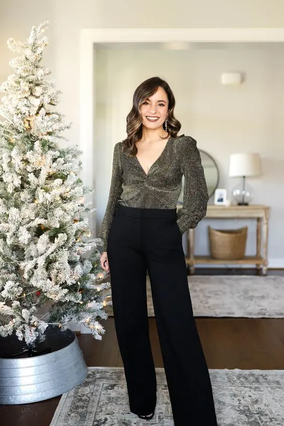 A catchy NYE wedding guest look with a shiny blouse with a V neckline, black trousers and shoes is adorable