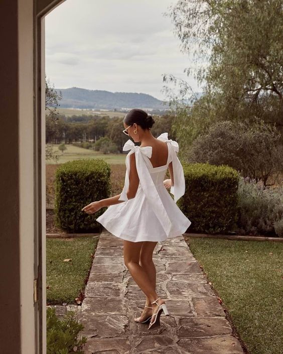 a catchy and fashionable look with a white mini dress with bows on the shoulders, white strappy shoes is a super cute idea