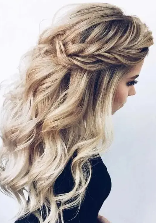 a chic wedding half updo with braids on the front, waves down and a messy volume on top for a romantic bride