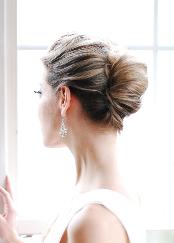 a classic chingon wedding updo with a messy volumetric top is a cool and elegant wedding hairstyle
