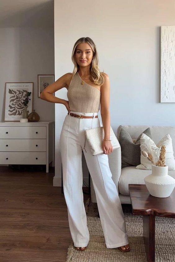 a classy and more relaxed graduation look with a nude one shoulder top, white pants, a brown belt, nude shoes and a large clutch