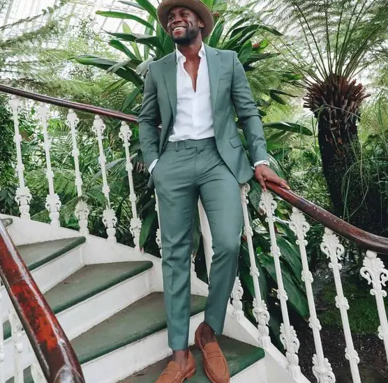 a cool beach wedding guest look with a green pantsuit, a white shirt, amber loafers and a hat