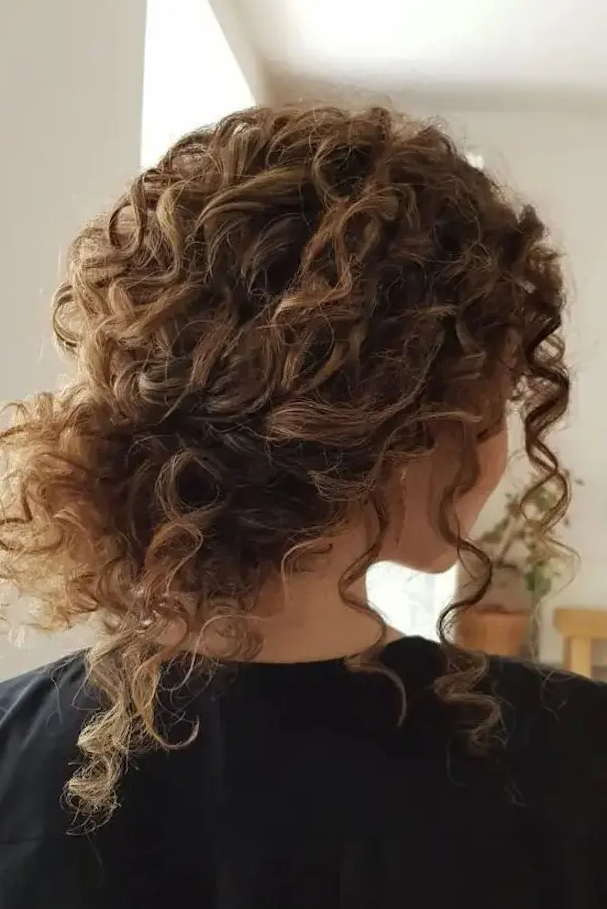 a curly messy low bun with bangs is a timeless idea for girls with curls - looks very pretty and relaxed