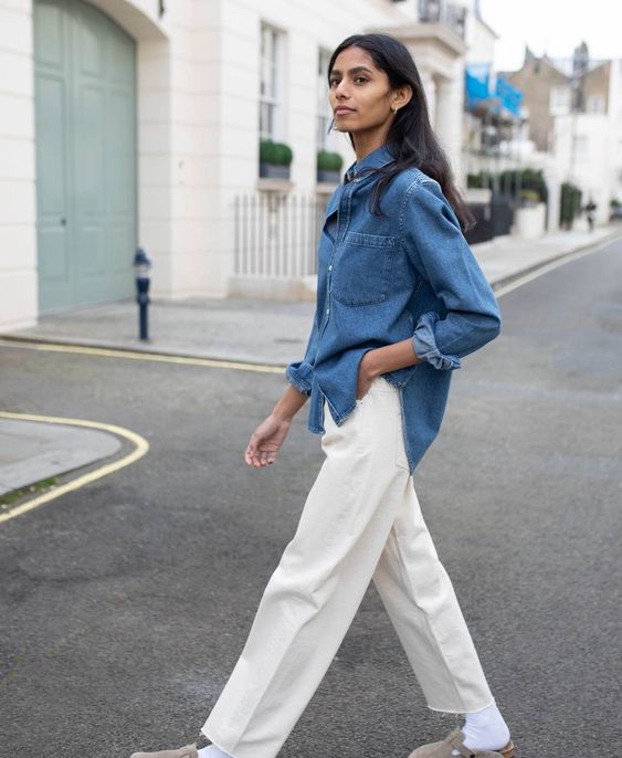a double denim look with a blue denim shirt, white jeans, white socks and grey slipper mules is perfect for spring