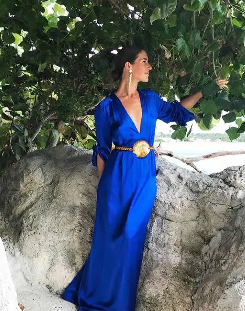 a fantastic bright blue maxi gown with a plunging neckline, long sleeves, statement earrings and a belt