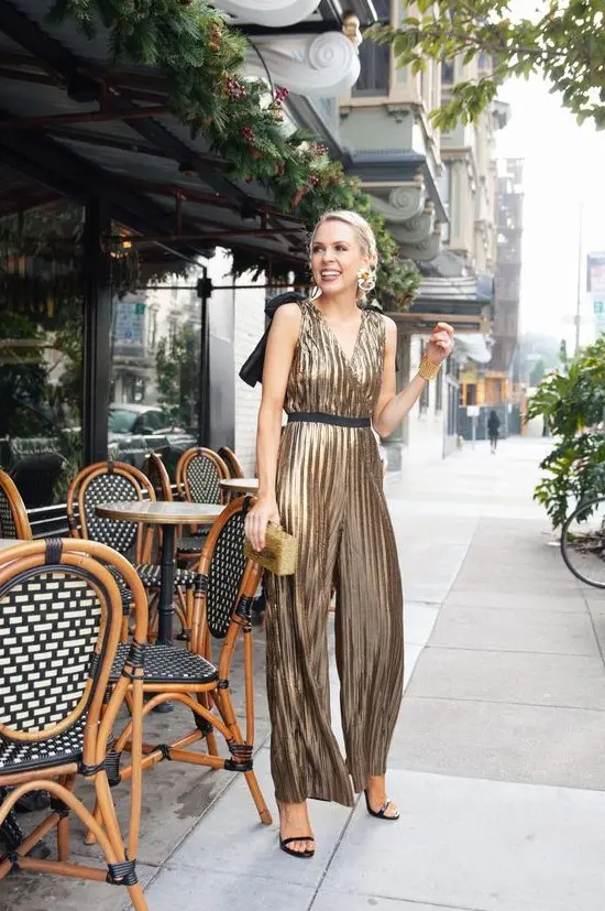 A gold metallic jumpsuit with a V neckline and wide straps, black strappy shoes and a gold clutch for NYE