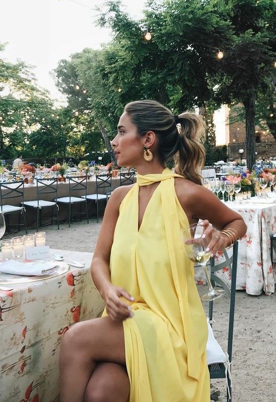 a lovely and flowy yellow dress with a matching scarf and statement earrings is a great idea for a hot day wedding or a beach one