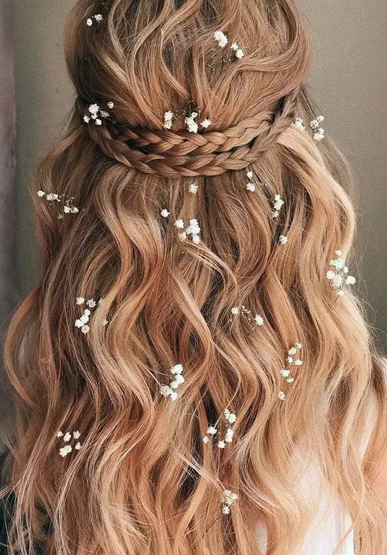 a lovely wedding half updo with a braided halo, waves down and some baby's breath tucked into the hair is idea for summer