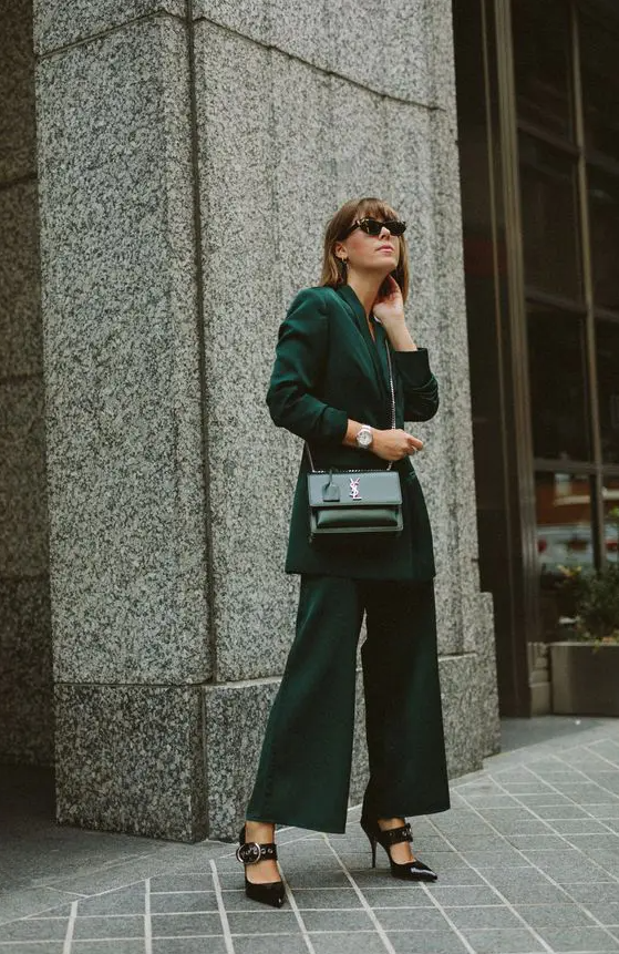 a lovely winter wedding guest outfit with a dark green pantsuit, an oversized blazer, wideleg pants, black shoes and a black bag