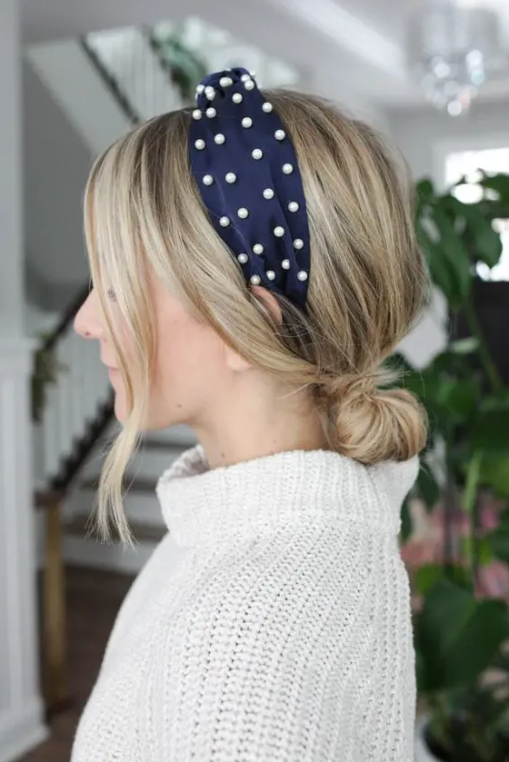 a low bun with a volume on top, face-framing bangs and a navy pearl headband are a chic and feminine combo to try