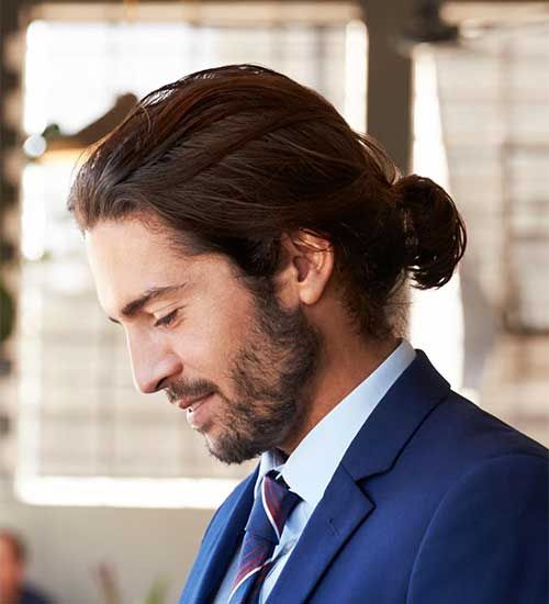 a men bob styled with a small and short ponytail with messy hair to make the look less formal