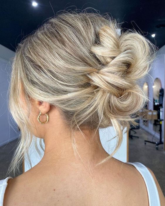 a messy updo with a bump on top and face-framing hair is a lovely medium length hairstyle for a wedding