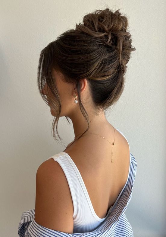 A messy wrapped wavy updo with a messy top and face framing hair is a sexy and cool wedding hairstyle