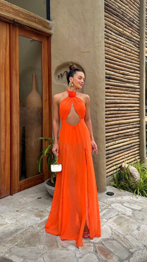 a neon orange maxi dress with a cutout frond and a loop on the neck, orange shoes and a tiny bag for a beach wedding