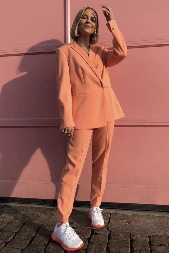 a peachy pantsuit with an oversized blazer and white and orange trainers for more comfortable walking and a sporty touch in the outfit