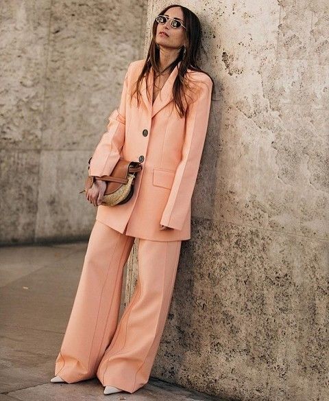 a peachy pink pantsuit with an oversized blazer, wideleg pants, white shoes and a small woven bag is a stylish idea