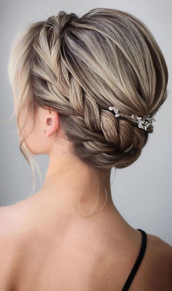 A pretty braided wedding updo with a bump on top and a large braid plus some face framing hair