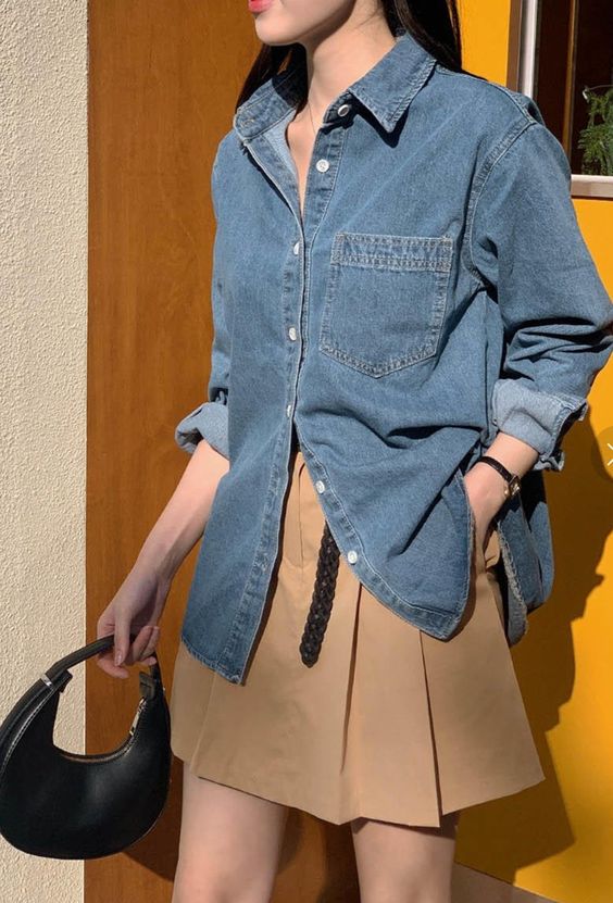 a pretty spring outfit with a blue denim shirt, a beige pleated mini and a small black bag is cool