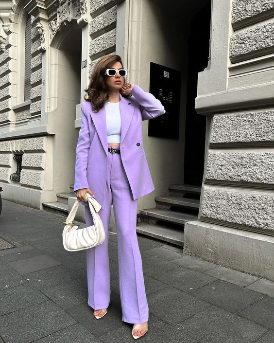 a purple pantsuit with an oversized blazer and flare pants, a white crop top, a white bag and a black belt are a great and colorful look for graduation