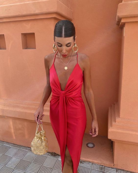 a red spagheti strap midi dress, statement gold jewelry and a small gold bag for a beach wedding