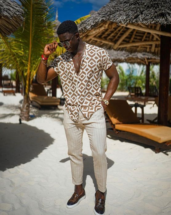 a relaxed beach wedding guest look with a printed short sleeve button down, striped pants, loafers and layered necklaces