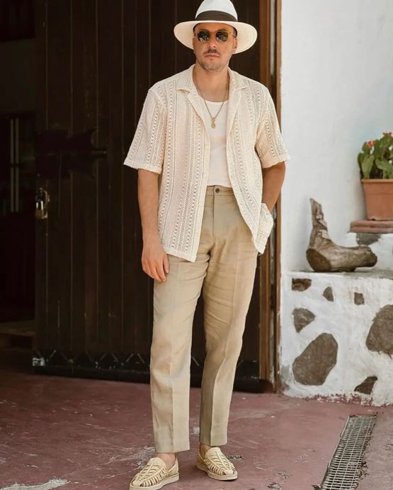 a relaxed beach wedding guest look with a white top, a neutral short sleeve button down, tan pants, loafers and a hat