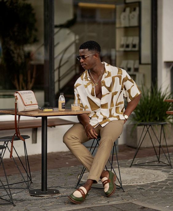 a relaxed beach wedding guest outfit with a printed button down, beige pants, loafers and sunglasses is lovely