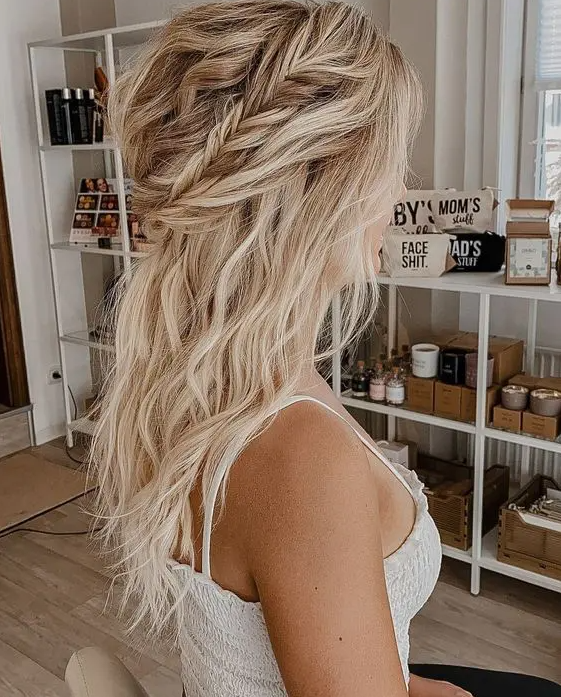 a romantic and relaxed wedding half updo with a twisted and braided halo, with waves down and a messy and wavy bump on top
